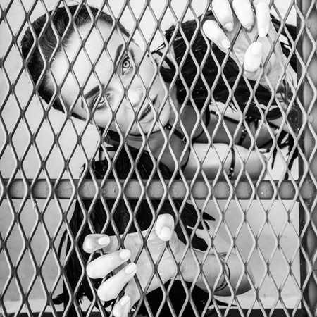 Closeup portrait of sensual beautiful angel woman looking up trapped in the cage - black and white...