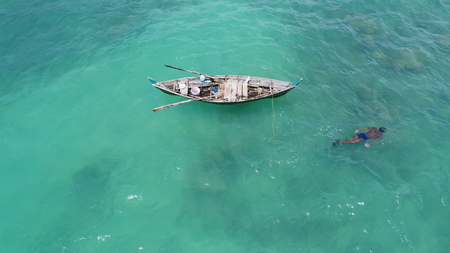 Aerial top view of boat on the sea and fisherman in the water hunting