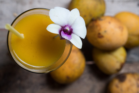 Top view of mango smoothie with straw and fruits on the wooden table background