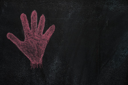 Hand shape drawn with red chalk on blackboardの写真素材