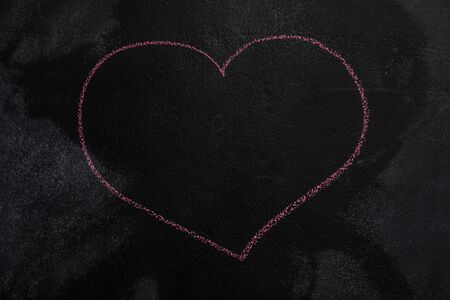 Red empty heart shape drawn with chalk on blackboardの写真素材