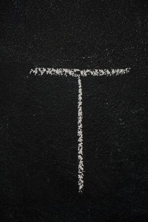 Letter T drawn with white chalk on blackboard. Education, school conceptの写真素材