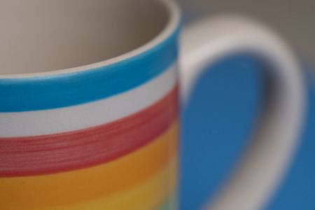 Closeup of colorful striped ceramic cup isolated over blue backgroundの写真素材