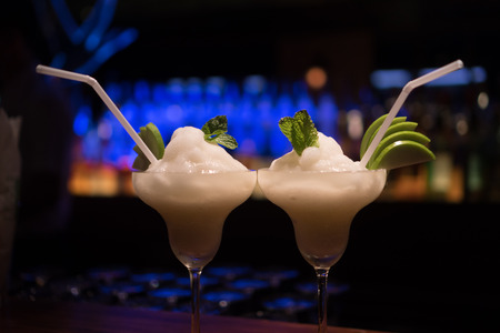 Closeup of two alcohol fruit coctail drinks on the table over blurred  bar restaurant backgroundの写真素材