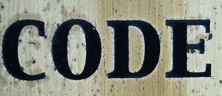 Word "code" in black letters isolated on rusty metal backgroundの写真素材
