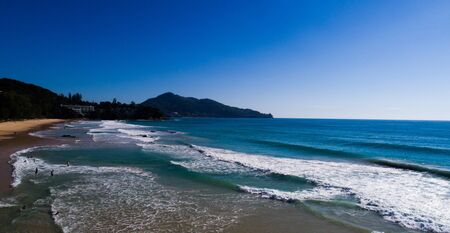 Aerial drone view of people on the beautiful tropical island beach and sea waves during sunny summer dayの写真素材