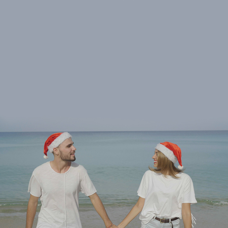 Christmas beautiful beach couple wearing Santa hat in summer sun in love on travel holidays on tropical travel destination during winter holidaysの写真素材
