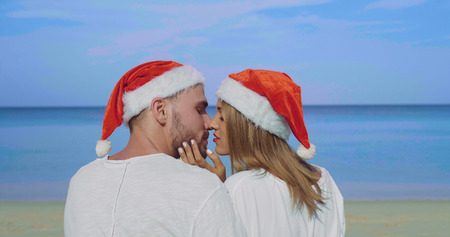 Christmas beautiful beach couple wearing Santa hat in summer sun in love on travel holidays on tropical travel destination during winter holidaysの写真素材