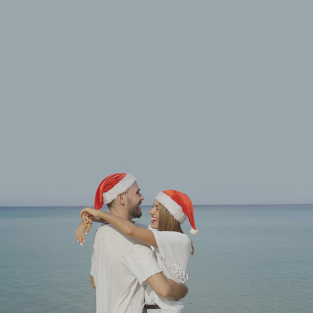 Christmas beautiful beach couple wearing Santa hat in summer sun in love on travel holidays on tropical travel destination during winter holidaysの写真素材