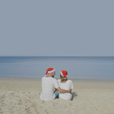 Christmas beautiful beach couple wearing Santa hat in summer sun in love on travel holidays on tropical travel destination during winter holidaysの写真素材