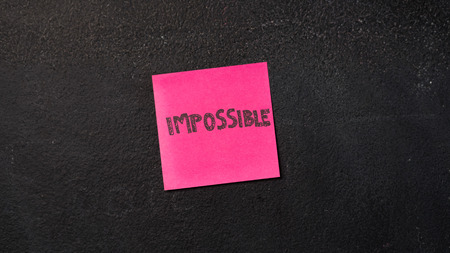 Sticky note with Impossible word on the blackboard