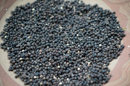 Closeup dried black pepper on the rustic clay brown plate