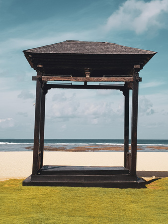 Wooden gazebo on the sandu beach against blue ocean and summer sky backgroundの写真素材