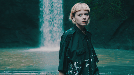 Beautiful fashion girl posing in tropical rain forest jungle near the waterfall. Portrait of stylish...