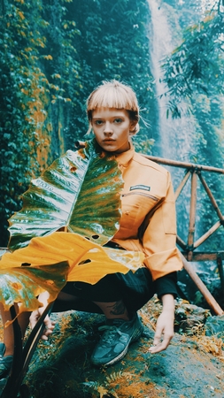 Beautiful fashion girl posing in tropical rain forest jungle near the waterfall. Portrait of stylish...