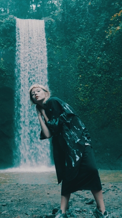 Beautiful fashion girl posing in tropical rain forest jungle near the waterfall. Portrait of stylish...