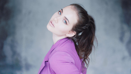 Closeup face of woman with amazing eyes. Fashion beauty portrait of girl in purple blazer isolated...