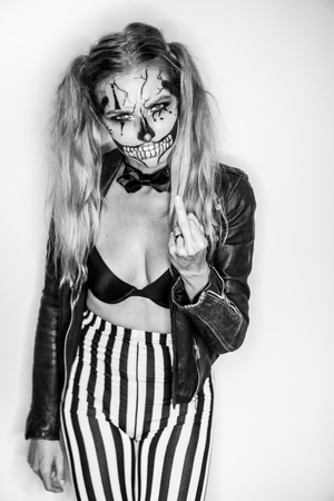 Woman with creepy Halloween clown skull makeup looking into the camera. Creative, artistic, Halloween concept - black and white photoの写真素材