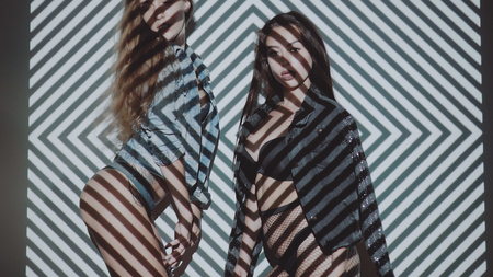 Two beautiful women in lingerie and jacket posing with projected pattern on them. Music, nightclubs, shows and entertainment conceptの写真素材