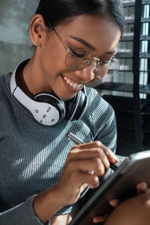Portrait of beautiful smiling girl with headphones drawing on her tablet at home. People, freelance...