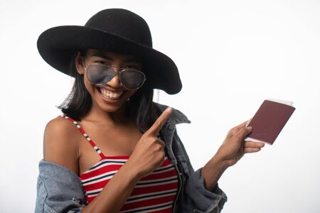 Portrait of smiling young Asian woman holding passport isolated over white wall background. People lifestyle, travel conceptの写真素材