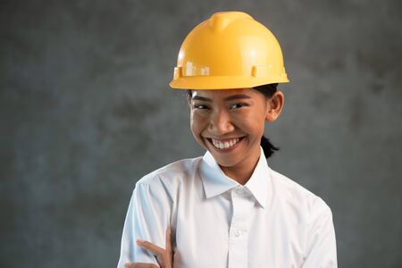 Portrait of smiling attractive Asian woman engineer over concrete wall backgroundの写真素材