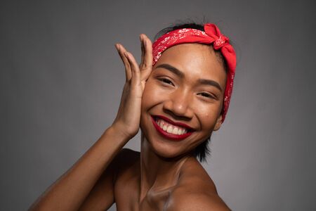 Portrait of smiling pretty Asian pinup girl isolated over gray wall backgroundの写真素材