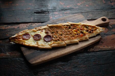 Turkish pide with sausage, beef and vegetables isolated on rustic wooden tableの写真素材