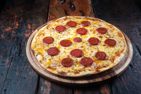 Fresh tasty pizza with Turkish sausage and mozzarella cheese isolated on rustic wooden backgroundの写真素材