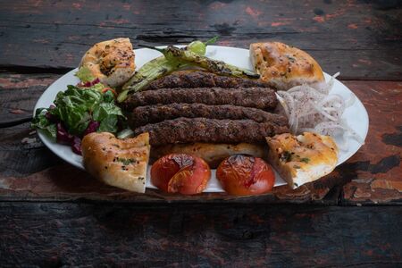 Turkish Mardin lamb kebab with bread and vegetables isolated on rustic wooden tableの写真素材