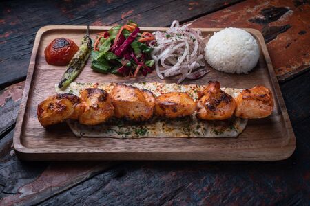 Turkish chicken sis kebab with rice and vegetables isolated on rustic wooden tableの写真素材