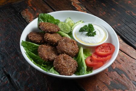 Falafel, vegan roasted chickpeas patties with garlic yogurt sauce isolated on rustic wooden tableの写真素材