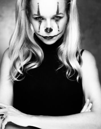 Halloween clown woman portrait posing over concrete wall background - black and white photoの写真素材