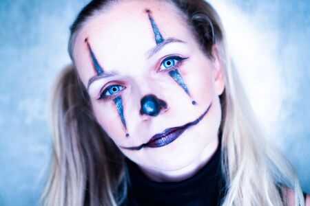 Halloween clown woman portrait posing over concrete wall backgroundの写真素材