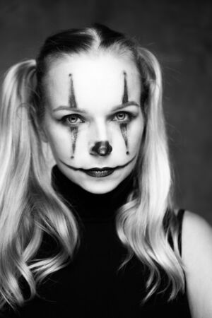 Halloween clown woman portrait posing over concrete wall background - black and white photoの写真素材