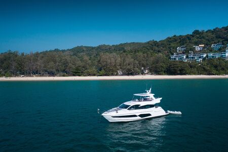 Aerial drone view of luxury white yacht in the blue sea with beach in the background. Travel conceptの写真素材