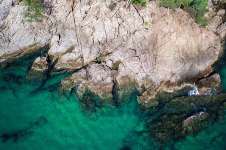 Aerial drone top view of turquoise sea surface with stones and rocks in waterの写真素材