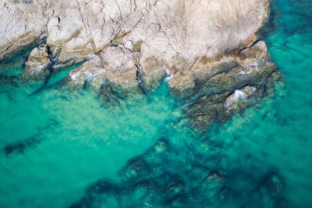 Aerial drone top view of turquoise sea surface with stones and rocks in waterの写真素材