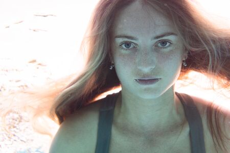 Closeup face of beautiful woman swimming underwaterの写真素材