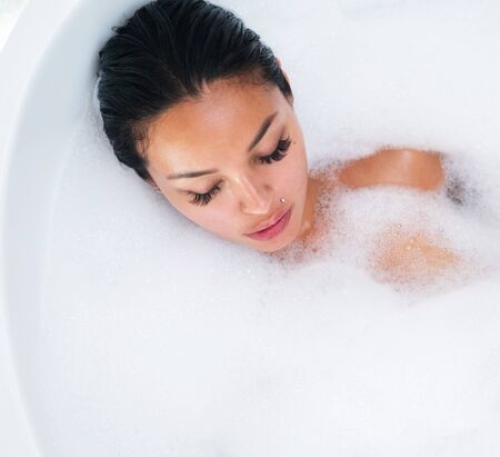 Top view portrait of beautiful and sensual brunette woman relaxing in bathtub with foamの写真素材