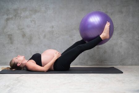 Portrait of pretty pregnant woman exercises with fitball in the gym. Working out and fitness, pregnancy conceptの写真素材