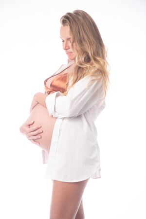 Pretty pregnant woman touching her belly while standing over white background. Maternity conceptの写真素材