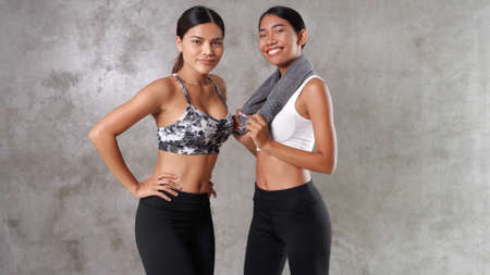 Two beautiful young Asian women at the gym. Happy female friends spending their free time at the sport centreの写真素材