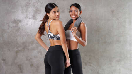 Two beautiful young Asian women at the gym. Happy female friends spending their free time at the sport centreの写真素材