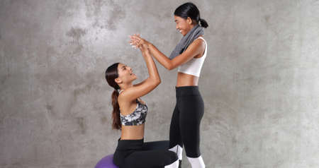 Two beautiful young Asian women at the gym. Happy female friends spending their free time at the sport centreの写真素材