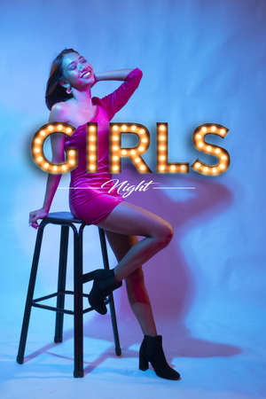 Beautiful Asian smiling girl in pink dress and black heeled ankle boots posing while sitting on the high chair. spotlight. Sexy disco woman, girls night party banner conceptの写真素材