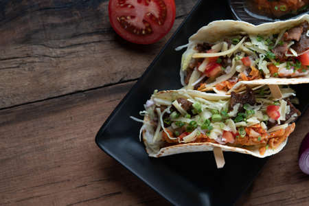 Slow cooked short ribs on tortillas with a spring onion tomato salsa isolated on wooden tableの写真素材