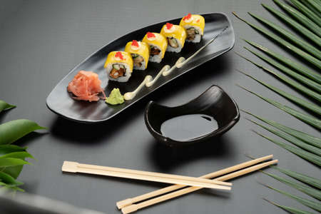 Deep-fried soft-shell crab, cucumber, mango, mayonnaise and tobiko isolated on black table with tropical leavesの写真素材