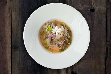 Prawns, white snapper, squid, salmon in a spicy orange dressing isolated on the wooden tableの写真素材