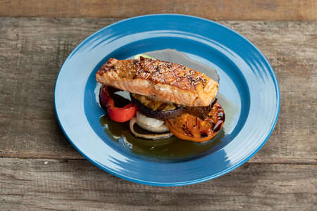 Grilled Salmon steak with vegetables isolated on rustic wooden tableの写真素材